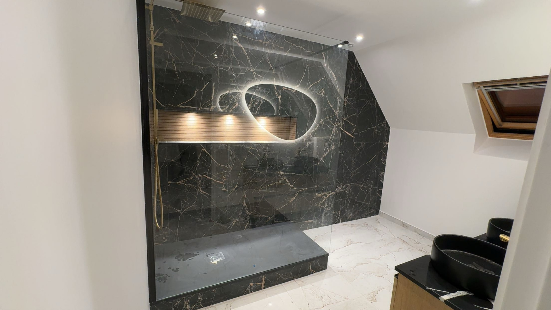 Salle de bains rénovée en marbre noir avec douche à l'italienne